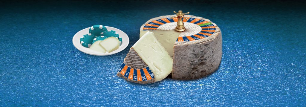 Plate of casino chips and cheese, beside roulette wheel in the shape of a cheese wheel.