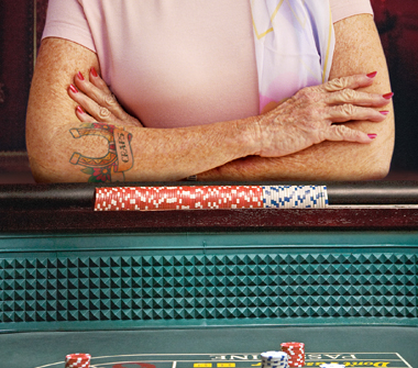A lady has her arms crossed with a tattoo that says “Craps”