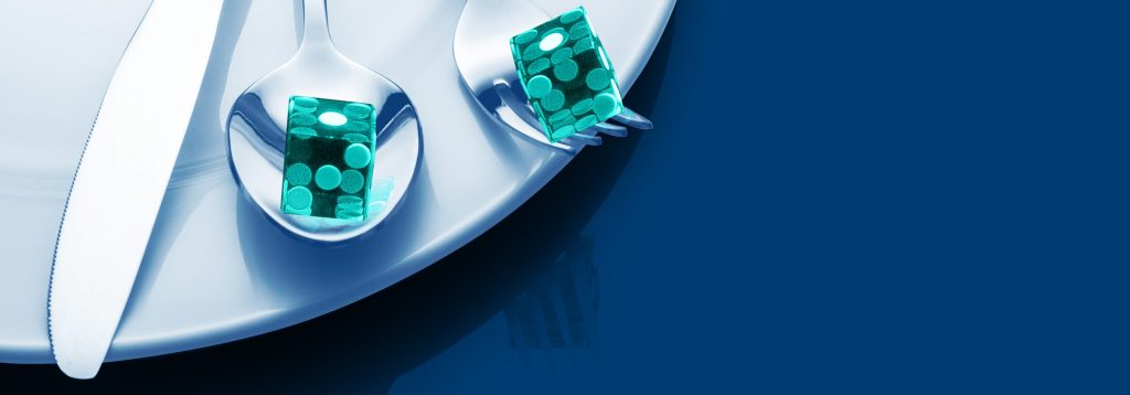 Un couteau, une cuillère et une fourchette sont sur une assiette. Il y a un dé sur la cuillère et un dé sur la fourchette.