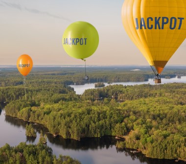 Trois ballons de plus en plus gros se succèdent. Le dernier à droite est une montgolfière. Les mots « Gros lot » sont inscrits sur chacun.