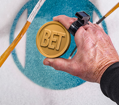 A hockey puck resembling a coin and with the word “bet” inscribed on it is held by a hand ahead of a puck drop.